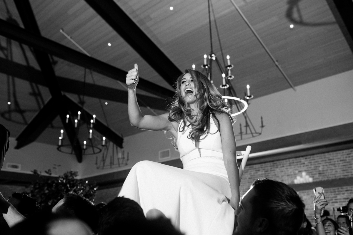 bride chair lift funny candid reception black and white Natirar 90 acres Mansion wedding peapack NJ new jersey lush greenery 