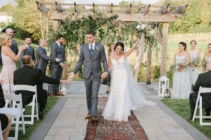 just married outdoor oriental rug rustic lanterns wooden trellis runner happy cheering bride and groom by the water Bear Brook Valley Wedding