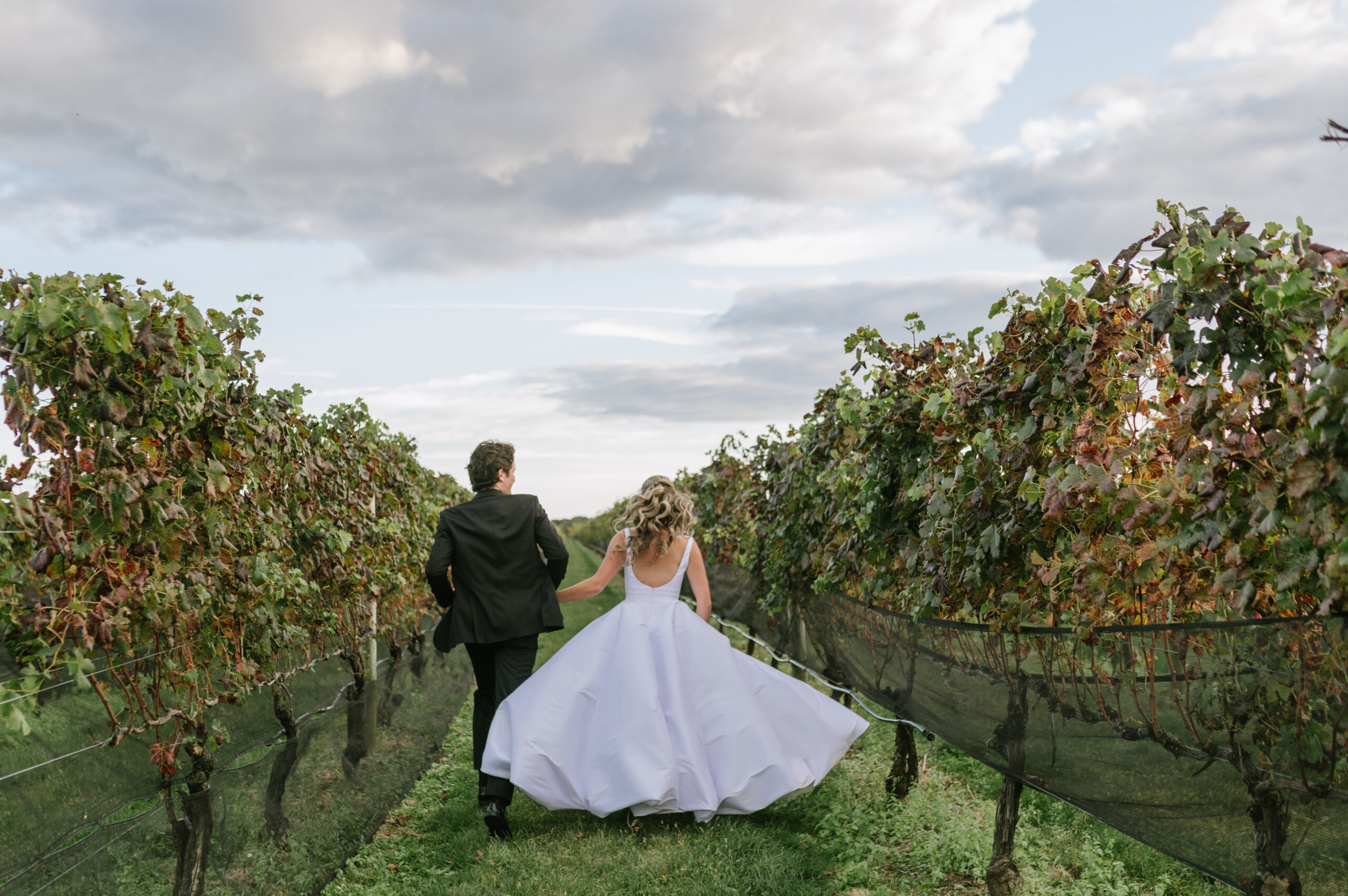 Acouple runs through the vineyard at Raphael Winery in Peconic New York on their wedding day